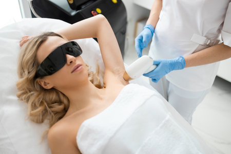 Female beautician removing hair of young woman's armpit with laser epilatorの写真素材