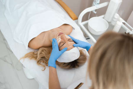 Cosmetologist doing facial massage with foamの写真素材