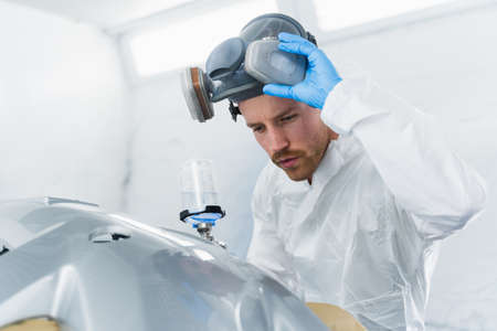 Young male car painter checks the quality of painting. Car service worker at workの写真素材