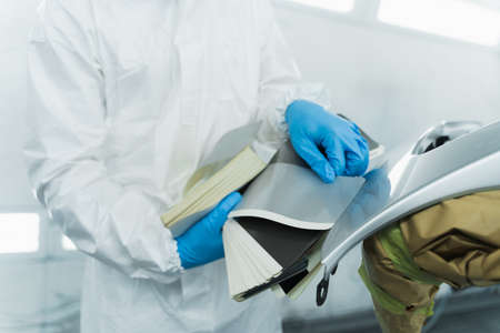 Auto painter leans samples of shades of paint colors against automobile elements. car painting conceptの写真素材