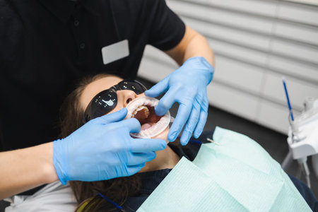 Female dental doctor puts a mouth dilator for comfort dental treatment to the patient