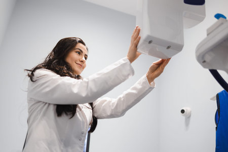Woman in a medical coat adjusts a dental tomograph. Medical worker in the X-ray room