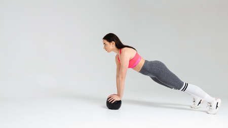 Athletic woman doing exercise with medicine ball on a white background in the studioの写真素材