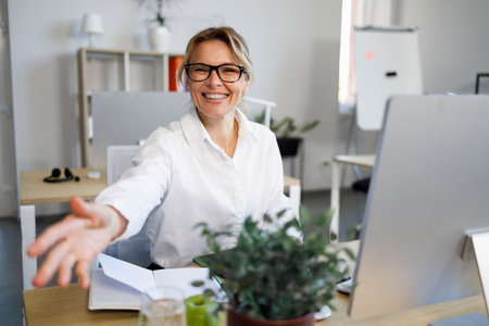 Friendly business woman giving hand for a handshake. Female consultant welcomes the client in the officeの写真素材