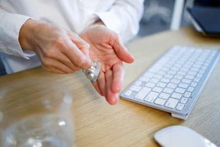 Close up view of business woman taking a pill from a blister packの写真素材