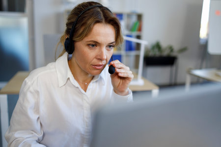 Female call center agent with a headset works on the support hotline