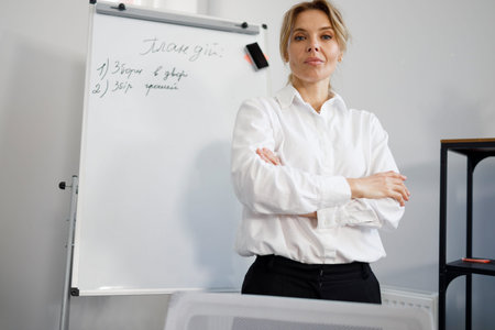Pretty businesswoman with crossed arms near magnetic white board