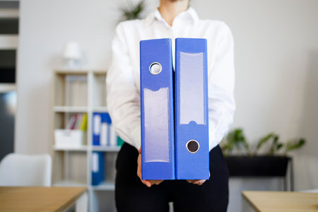 Secretary holds two blue folders with documents in her handsの写真素材