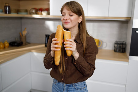 Pretty young woman sniffing a fresh french baguette