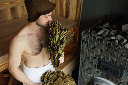 Man sniffs a bath broom during a spa treatment in the saunaの写真素材