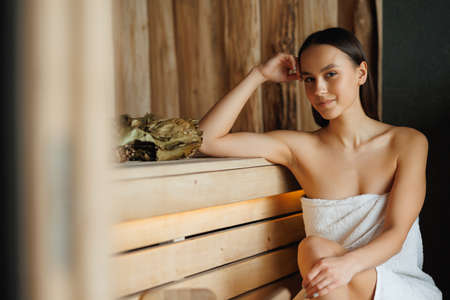Positive woman in towels relaxing in wooden saunaの写真素材