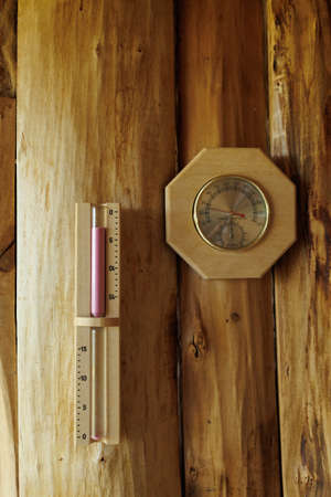 Sauna thermometer and hygrometer, hourglass on wooden wallの写真素材