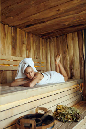 Young woman lying on wooden bench in saunaの写真素材