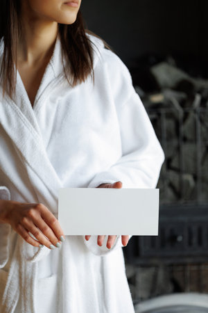 Woman in bathrobe with spa gift voucher in handsの写真素材