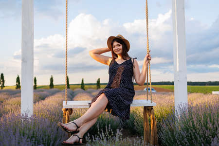 Pretty woman posing on a swing in a fieldの写真素材