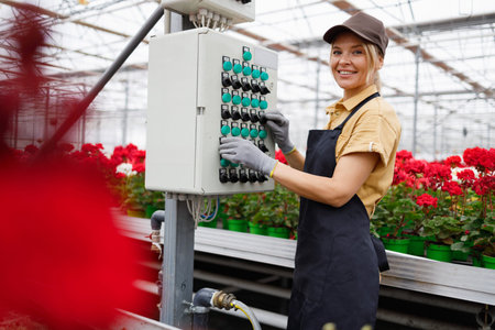 Beautiful woman in a flower greenhouse turns on electricity through the control panel