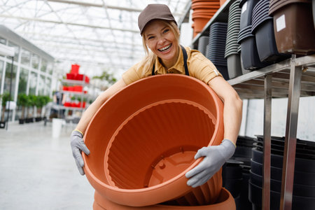 Satisfied woman working in plant pot department at garden store