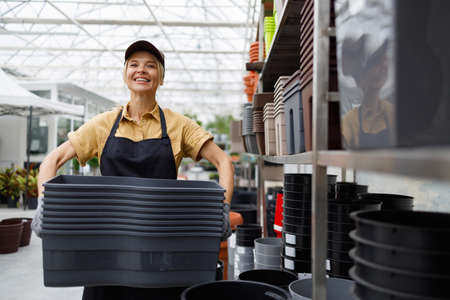 Portrait of a garden center worker with many flower pots in her handsの写真素材