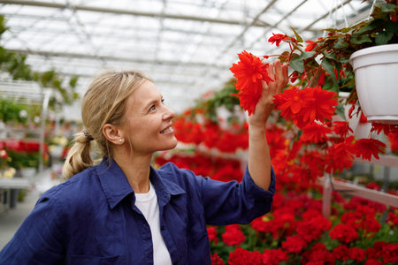 Pretty middle aged woman chooses flowers to buy in a greenhouseの写真素材