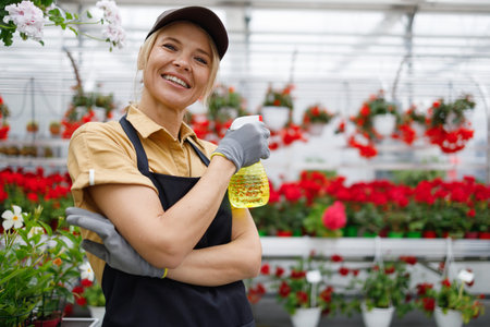 Portrait of beautiful woman florist with spray bottle in greenhouseの写真素材