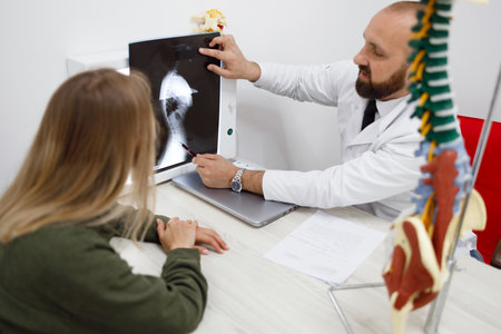 Male doctor analyzes with a patient the disease of the spine on an x-ray imageの写真素材