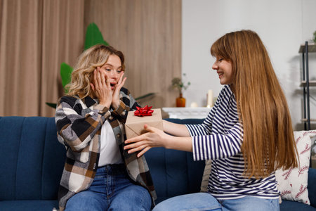 Mature woman sitting on the couch is delighted with her daughter's gift