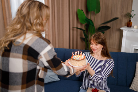 Loving mother gives a cake to her birthday daughterの写真素材