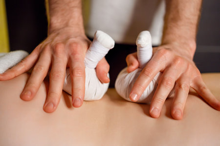 Close up woman receiving back massage with herbal bags in spa salonの写真素材