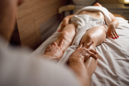 Hands of masseur massaging legs of woman in spa salonの写真素材