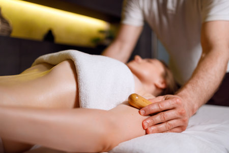 Woman enjoys a massage with bamboo sticks during a spa treatment session at a resortの写真素材