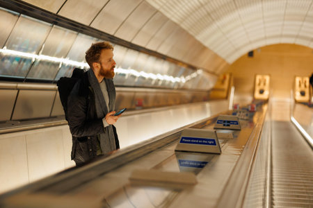 Bearded man with a smartphone on an escalator in the subwayの写真素材