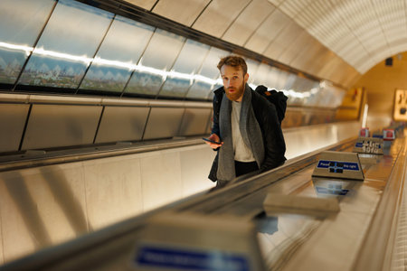Bearded man with a smartphone on an escalator in the subwayの写真素材