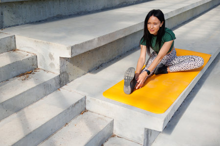 Young Sporty Woman Stretching on Yoga Mat at Sports Venueの写真素材