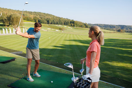 Active Couple Perfecting Golf Strokes Outdoorsの写真素材