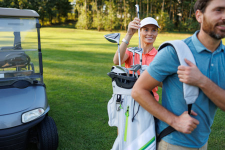 Golfing Partners: Woman Selecting Club from Bag on Courseの写真素材
