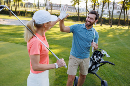 Celebrating Success: Young Couple Gives High Five on Golf Courseの写真素材