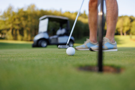Leisurely Golf: Man, Cart, and Course Holeの写真素材