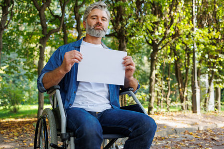 Nature's Embrace: Wheelchair-bound Man with Paper Outdoorsの写真素材