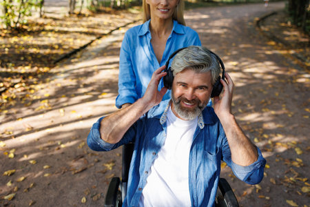 Inclusive Park Stroll: Woman Assists Friend in Wheelchair Amidst Nature's Beauty