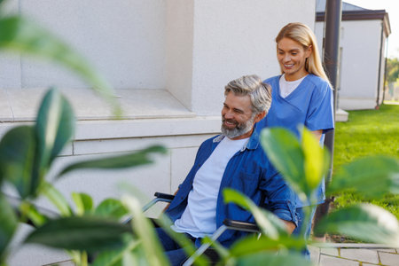 Accessibility in Motion: Nurse Assists Wheelchair User Outdoorsの写真素材