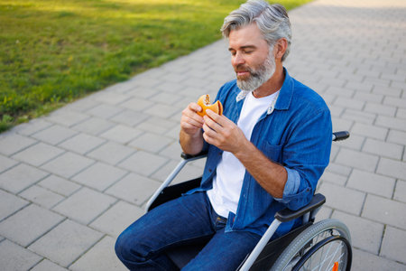 Inclusive Dining: Man in Wheelchair Eating Burger Outdoors