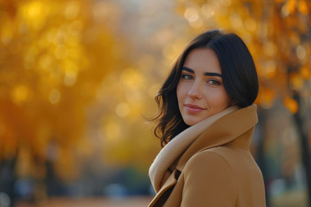 Elegant Woman in Autumn Coat Among Golden Treesの素材