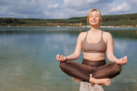 Nature Break: Girl in Sportswear Sitting by the Lakeの写真素材