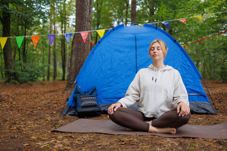 Athletic Fair-Haired Girl Relaxing on a Caremat in a Serene Forest Settingの写真素材