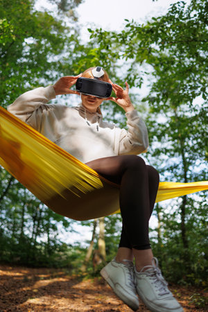 Serene Escape: Young Girl Enjoying Virtual Reality in a Hammockの写真素材