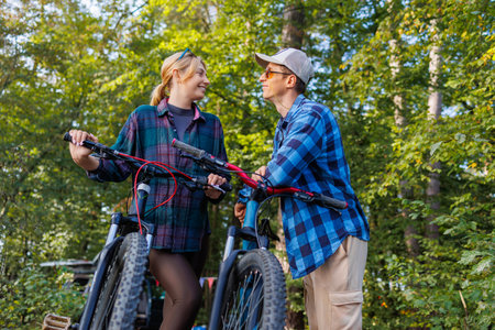 Young couple man and woman with bicycles on nature talking to each other smilingの写真素材