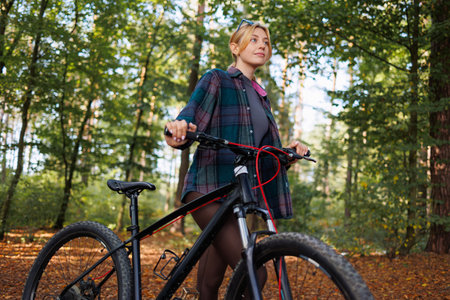 Young woman with a bicycle in the forest looking awayの写真素材