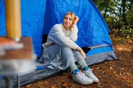 Cute young woman is sitting in a tent in nature