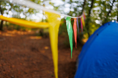 Carnival colorful garland,blue tent and yellow hammock in forestの写真素材