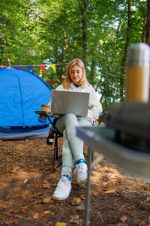 Girl works on a laptop in the forest at a campsiteの写真素材